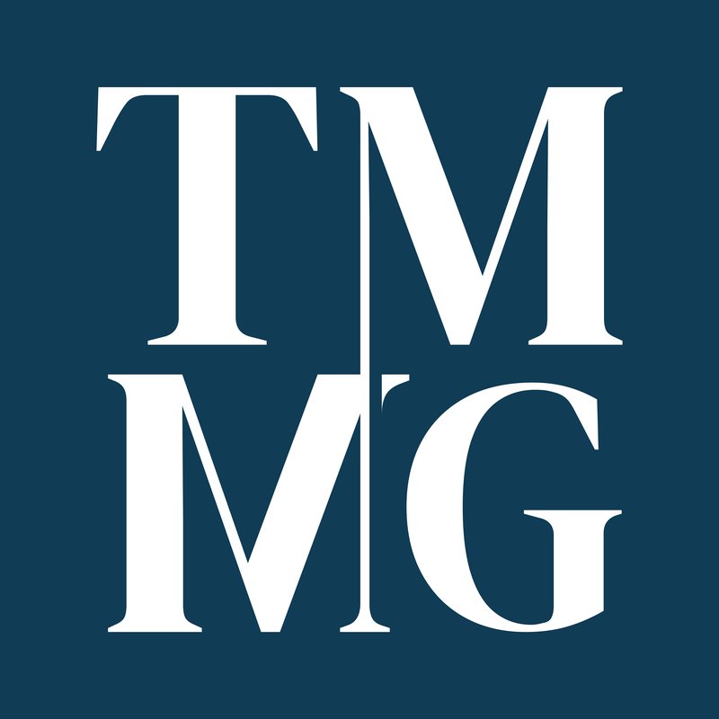 The McLoughlin Medical Group TMMG monogram designed by Heart IT: stacked TM/MG letters in a classical serif on a deep navy background